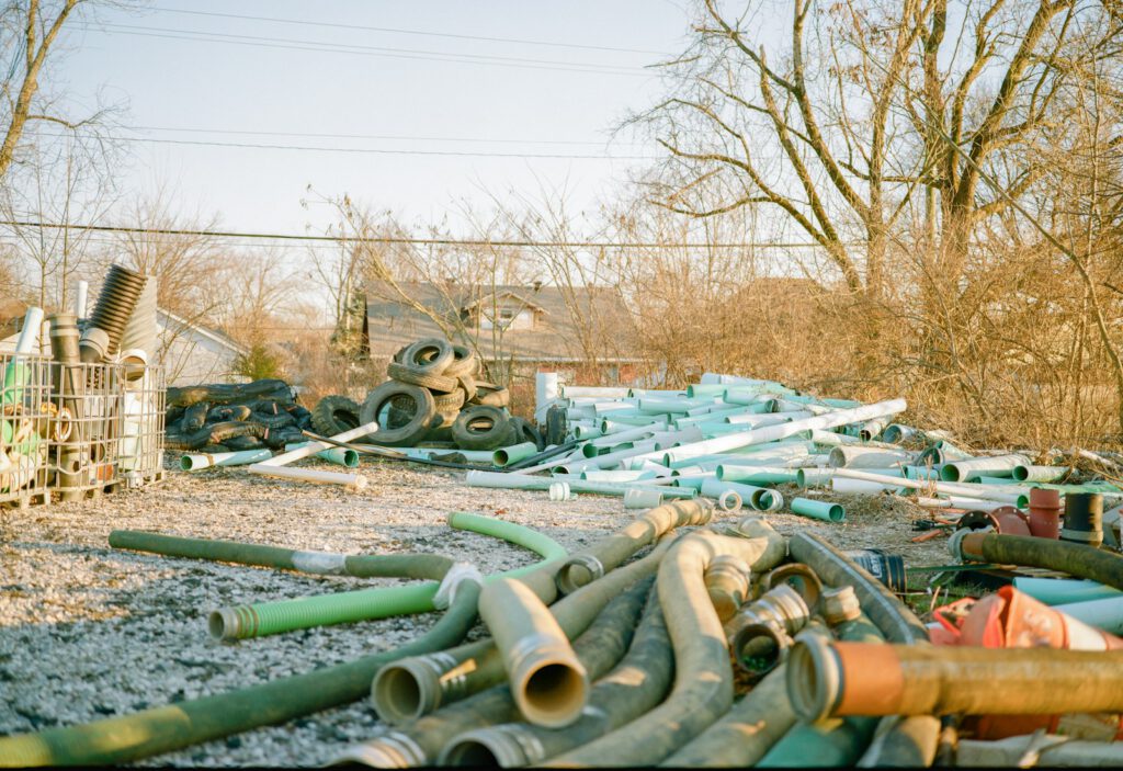 Photo by Jake Johnson a pile of pipes sitting on top of a dirt field