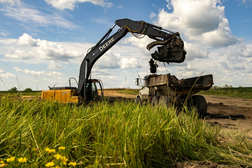 Photo by LEGENDERRY Excavator dumping dirt into a dump truck